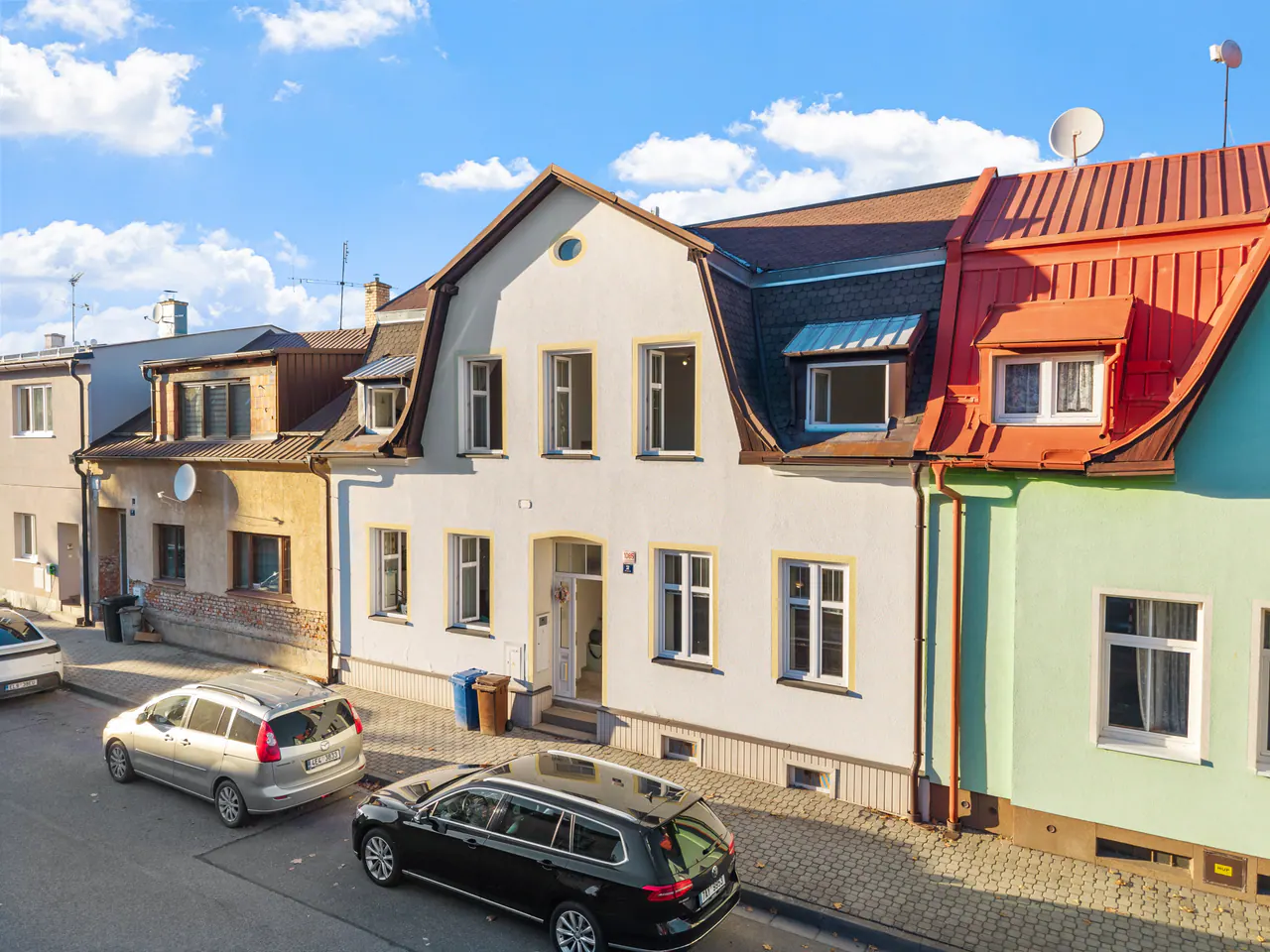 Uliční průčelí domu s mansardovou střechou v řadě měšťanských domů