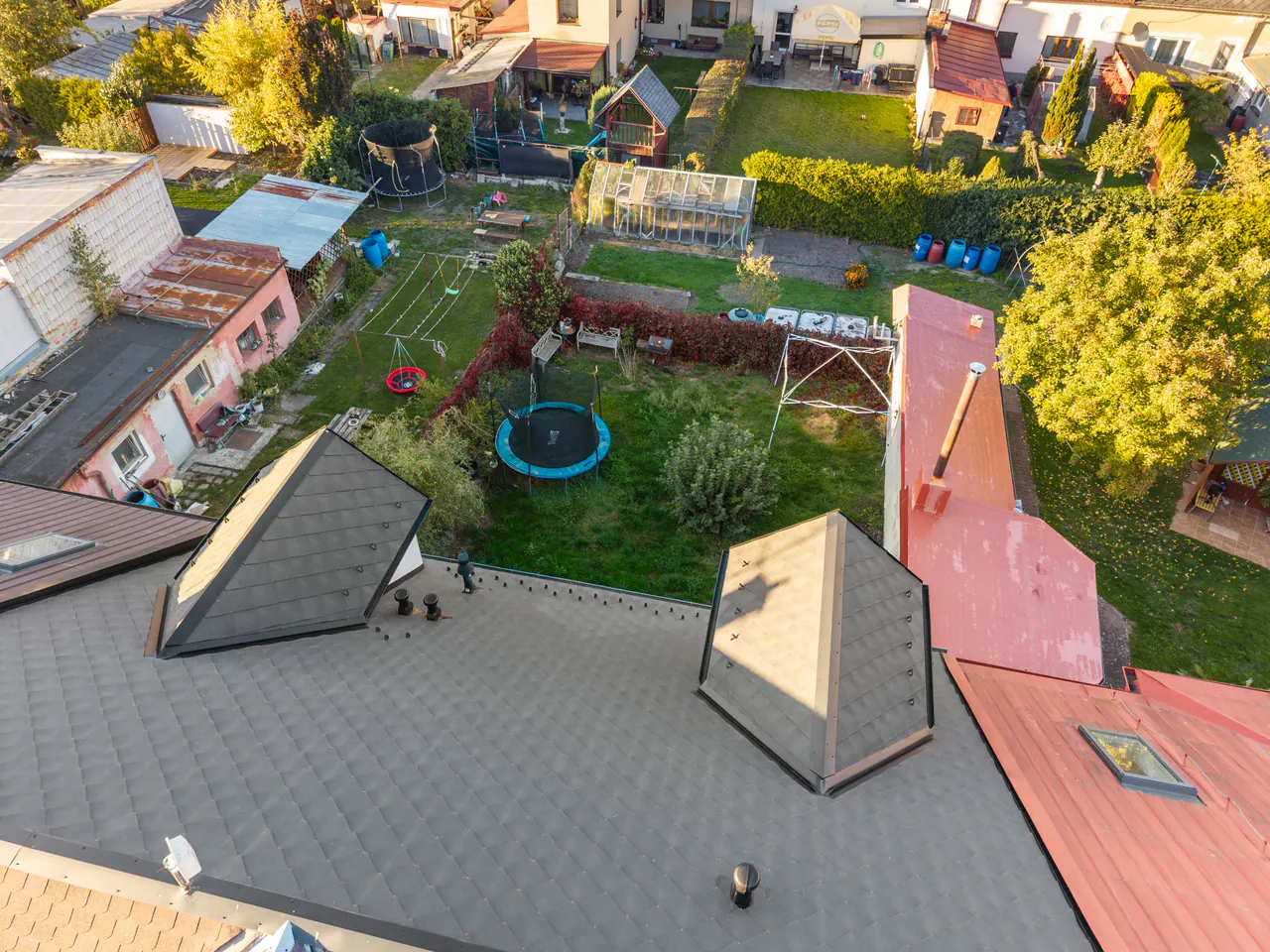 Pohled z dronu přes střechu domu na zahrady za domy