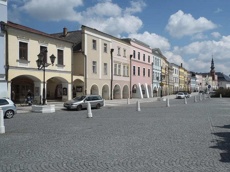 Řada domů s podloubím na náměstí Míru, v pozadí věž kostela.
